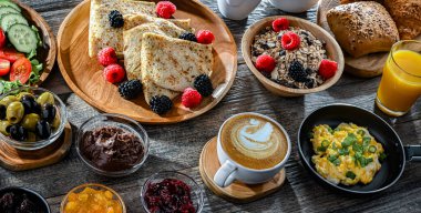 Kahvaltının yanında kahve, portakal suyu, kruvasan, mısır gevreği, çırpılmış yumurta ve krep var..