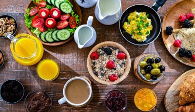 Kahvaltının yanında kahve, portakal suyu, kruvasan, mısır gevreği, çırpılmış yumurta ve krep var..