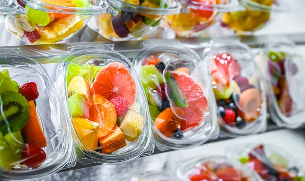 Plastic boxes with pre-packaged fruit salads, put up for sale in a commercial refrigerator