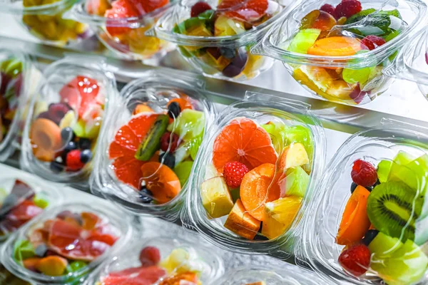 Plastic boxes with pre-packaged fruit salads, put up for sale in a commercial refrigerator