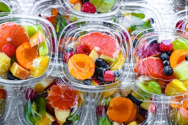 Plastic boxes with pre-packaged fruit salads, put up for sale in a commercial refrigerator