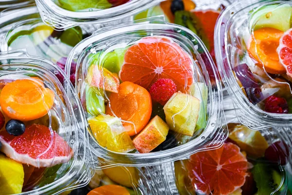 Plastic boxes with pre-packaged fruit salads, put up for sale in a commercial refrigerator