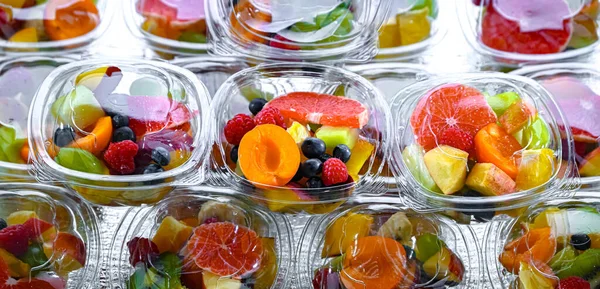 Plastic boxes with pre-packaged fruit salads, put up for sale in a commercial refrigerator