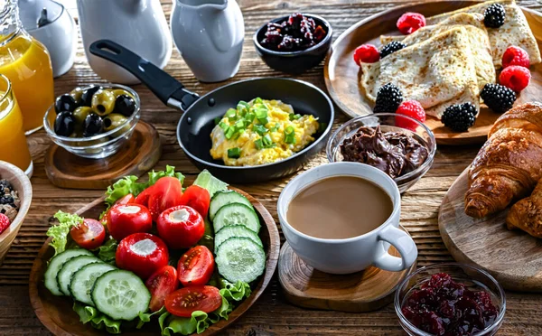 Kahvaltının yanında kahve, portakal suyu, kruvasan, mısır gevreği, çırpılmış yumurta ve krep var..