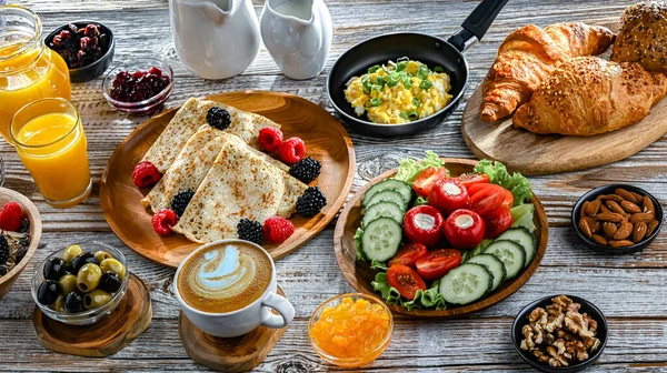 Kahvaltının yanında kahve, portakal suyu, kruvasan, mısır gevreği, çırpılmış yumurta ve krep var..