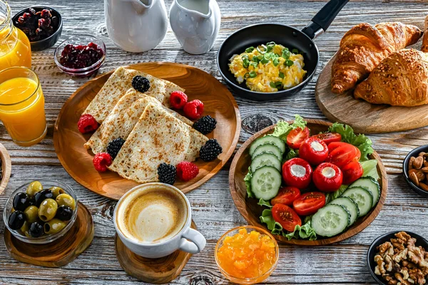 Kahvaltının yanında kahve, portakal suyu, kruvasan, mısır gevreği, çırpılmış yumurta ve krep var..