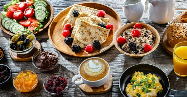 Kahvaltının yanında kahve, portakal suyu, kruvasan, mısır gevreği, çırpılmış yumurta ve krep var..