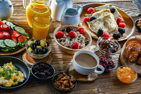 Kahvaltının yanında kahve, portakal suyu, kruvasan, mısır gevreği, çırpılmış yumurta ve krep var..