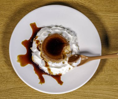 Lezzetli vanilyalı krema, karamel sos ve kaşık ile yumurta muhallebi. Krem çevreleyen