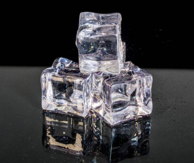 Küçük beyaz ve şeffaf buz küpleri yığını izole siyah arka plan yansıtan