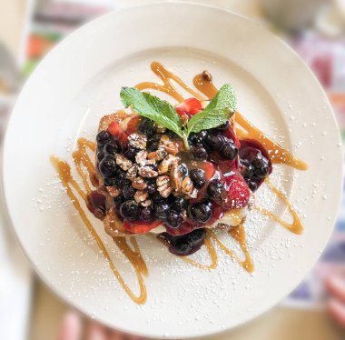 Fransız tostu çilek, çilek, ceviz ve damlama akçaağaç şurubu ve nane ile beyaz plaka üzerinde bırakır. Sağlıklı tatlılar kavramı portre aşkına.