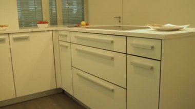 Elektrikli ocak ile modern beyaz mutfak tasarımı ve modern mutfak kuvars tezgah üst yan görünümü. Dolap ışıkları altında dekoratif bir mutfak tasarım konsepti olarak, gıda ve plats dahildir.