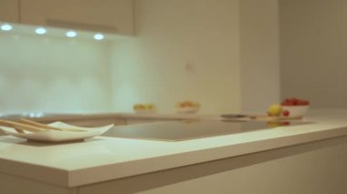 Modern mutfak dolabı, beyaz mutfak kuvars tezgah, elektrikli ocak ve mutfak lavabo güzel yavaş hareket. Dolap ışıkları altında dekoratif bir mutfak tasarım konsepti olarak, gıda ve plats dahildir.