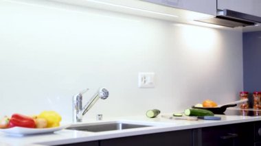 Modern kuvars levhatezgahı. Mutfak tezgahı krom lavabo ve musluk ile beyaz renkte yapılır. Mutfak dolapları modern siyah düz paneller yapılır.