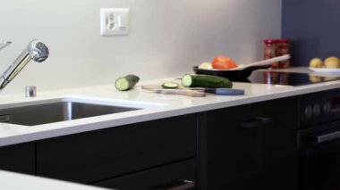 Mermer levhadan yapılmış modern mutfak tezgahı. Sayaç krom lavabo ve musluk ile modern beyaz renkte yapılır. Mutfak dolapları siyah düz panellerden yapılmıştır.