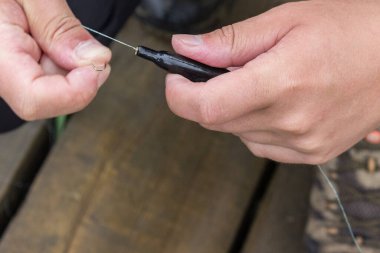 Adamın biri balık oltası tutuyor. nasırlı ve çamurlu kaba erkek elleri. Yumurtlama mevsiminde balık tutmaya hazırlanmak ve balıkçı günü konsepti