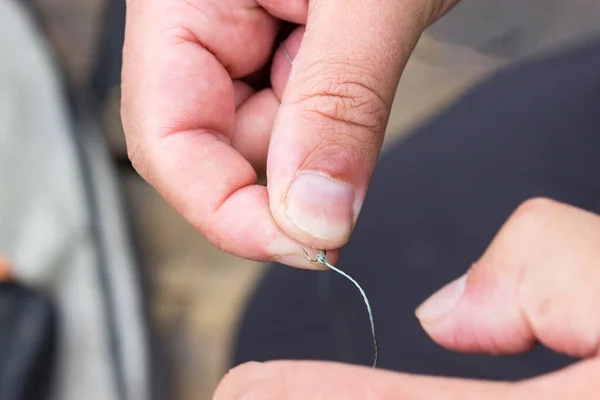 A man is holding a fish hook. rough male hands with calluses and dirt. Preparing for fishing during the spawning season and the concept for the day of the fisherman