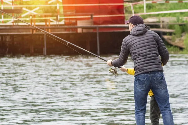 Father teaching his son fishing. concept of father\'s day. Father and son in yellow jacket fishing together