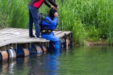Mavi bir dalgıç nehirde yüzer ve enkaz rezervuarını temizler. Çok tehlikeli bir iş. Tatil konsepti - dünya çevresi gündüz ve dünya su günü. Çevre koruma. Ekoloji