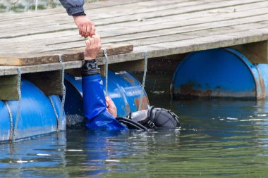 Mavi bir dalgıç nehirde yüzer ve enkaz rezervuarını temizler. Çok tehlikeli bir iş. Tatil konsepti - dünya çevresi gündüz ve dünya su günü. Çevre koruma. Ekoloji