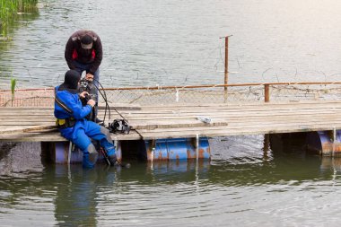 Mavi bir dalgıç nehirde yüzer ve enkaz rezervuarını temizler. Çok tehlikeli bir iş. Tatil konsepti - dünya çevresi gündüz ve dünya su günü. Çevre koruma. Ekoloji