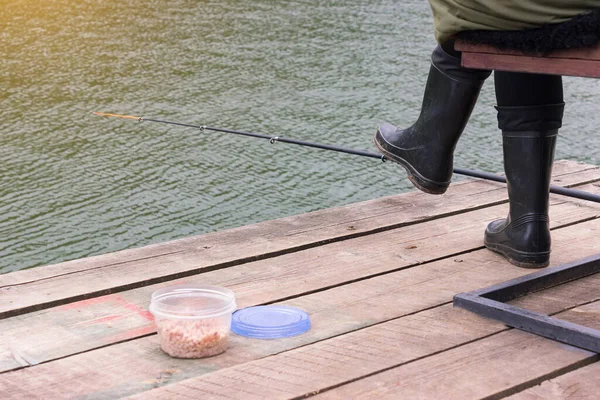 Uma Pessoa Botas Borracha Está Sentado Cais Madeira Pesca Uma — Fotografia de Stock