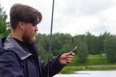 Sert bir Norveçli rıhtımda oturmuş oltayla balık tutuyor.. 
