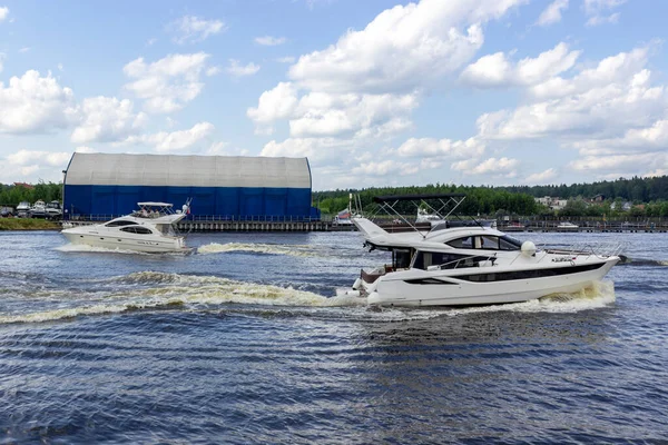Rusya, Mytishchi, 12.06.2020. Geniş bir su kanalında yüzen insanlarla dolu bir tekne. Sprey sineklerin kıç kısmından, suyun yüzeyinde izler bırakarak. Denizciler için eğlence. Sadece editör kullanımı.