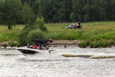 Rusya, Moskova, 15.06.2020. Motorlu tekne, kıyıya çok yakın bir hızla su kanalında yüzüyor. Sprey sineklerden, su yüzeyinde iz bırakarak. Sadece editör kullanımı.