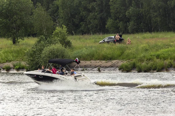 Rusya, Moskova, 15.06.2020. Motorlu tekne, kıyıya çok yakın bir hızla su kanalında yüzüyor. Sprey sineklerden, su yüzeyinde iz bırakarak. Sadece editör kullanımı.