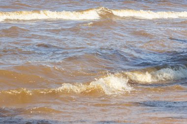 Gün batımında deniz dalgaları üzerinde kırmızı ve turuncu güneş ışığı yansıması ile yakın görüş. Doğa soyut bulanık su arka planı. metin ve okyanus günü konsepti için yer.