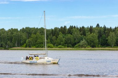 Rusya, Mytishchi, 17.07.2020. Beyaz bir yelkenli yatı, Moskova kanalı boyunca yeşil orman ve mavi gökyüzünün arka planına doğru ilerliyor. Sadece editör kullanımı