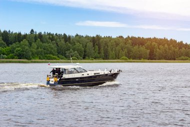 Rusya, Mytishchi, 18.06.2020. Nehir kanalı boyunca bir grup insanla birlikte uzun siyah bir motorlu tekne yola çıkıyor. Donanma günü ve arkadaşlarla balık tutma kavramı. Sadece editoryal kullanım..