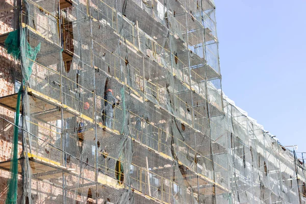 restoration of the building and the scaffolding is covered with a cloth for protection from dust and debris. the work of builders to maintain buildings in proper form.