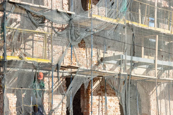 restoration of the building and the scaffolding is covered with a cloth for protection from dust and debris. the work of builders to maintain buildings in proper form.