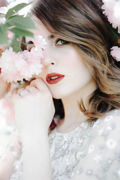 非常美丽的女孩新娘下了面纱 米色婚纱礼服附近的树樱正在往下看 — 图库照片