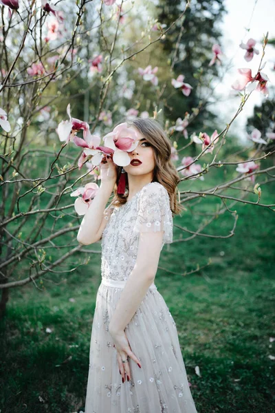 非常に美しい少女を自然下で桜の木の近くのベール ベージュ結婚式ドレス花嫁を探して — ストック写真