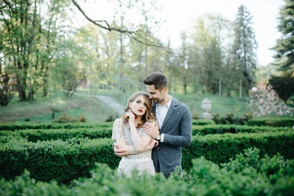 Пара в свадебной одежде с букетом цветов и зелени в руках на фоне поля на закате, невеста и жених — стоковое фото