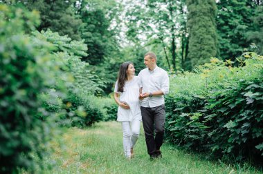 Mutlu ve genç hamile çift doğada sarılıyorlar.