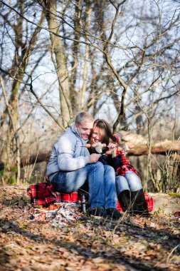 Rüzgârla oluşan kar yığını üzerinde çömelme ve ellerini ateşte ısınma sırasında konuşurken iki genç backpackers