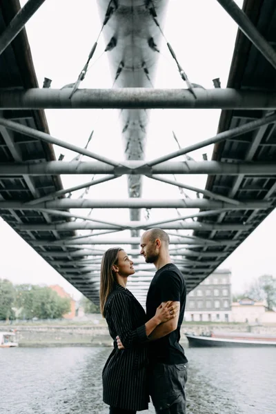 恋爱中的年轻夫妇站在山上挂着桥 抱着对方微笑着看着对方 — 图库照片