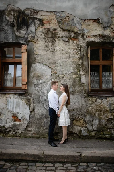 恋爱中的一对是在早晨的城市里 在灰色的城市墙上亲吻和拥抱 男人和女人在一起很开心 古老的欧洲古老城市街道与石墙 — 图库照片