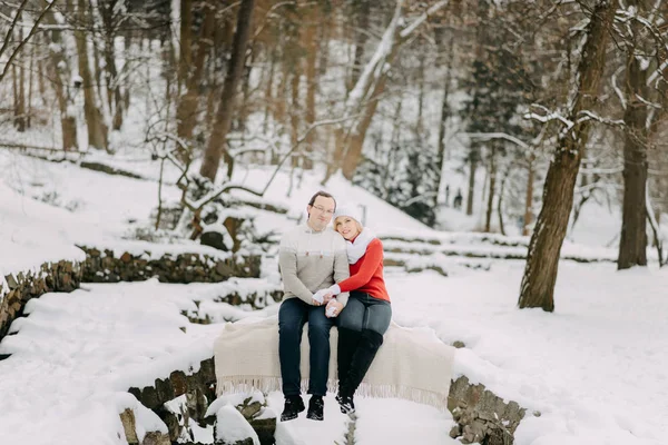 Una pareja de jóvenes amantes en chaquetas de invierno y bufandas sentados en un parque de nieve — Foto de Stock