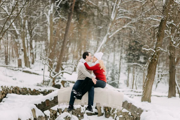Para zakochanych w kurtki zimowe i szaliki siedzi w parku snow — Zdjęcie stockowe