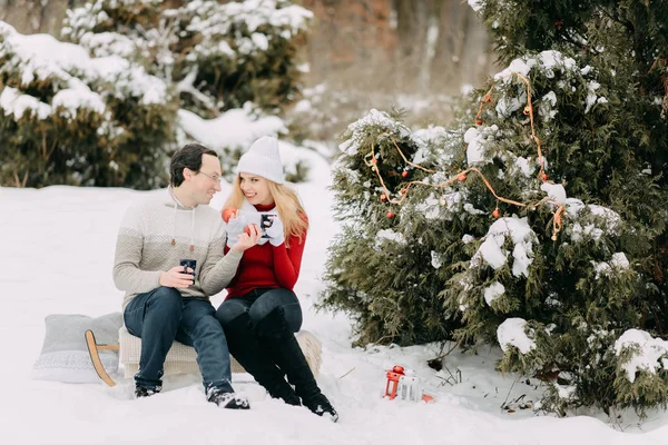 Щаслива пара взимку п'є чай і сидить на санях — стокове фото