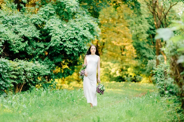 Gelukkig zwangere vrouw in een krans en een bouquet van veldbloemen o — Stockfoto