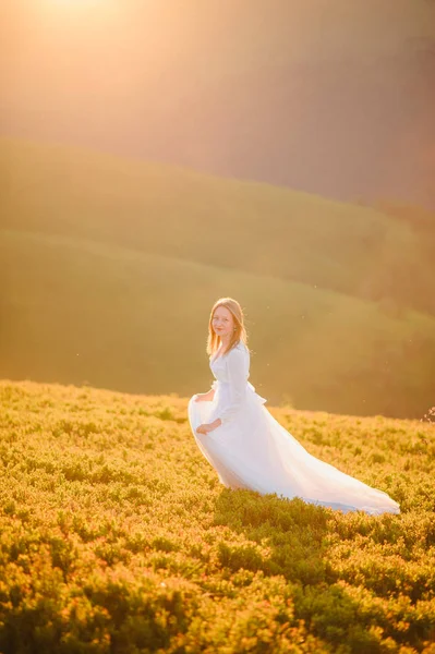 ウェディング ドレスを着た女性にまたがる山に向かってフィールド — ストック写真