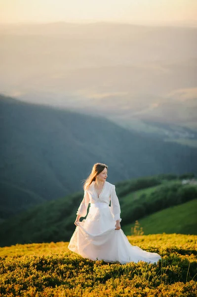 Donna in abito da sposa corre attraverso il campo verso le montagne — Foto Stock