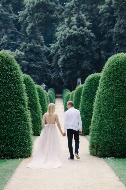 trendy genç bir çift şehirde yaz aylarında yürür, genç kadının bir lüks elbise giyer