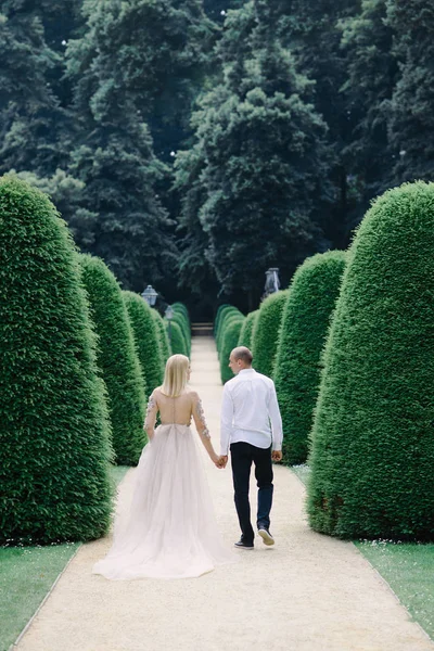 a trendy young couple walks in the city in summer, the young woman wears a luxury dress